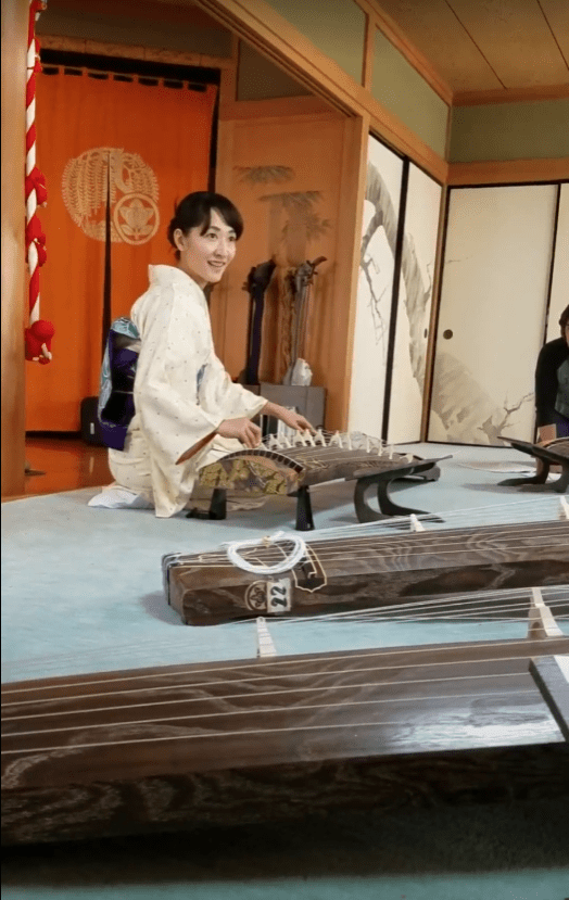 Japanese woman demonstrating koto string instrument