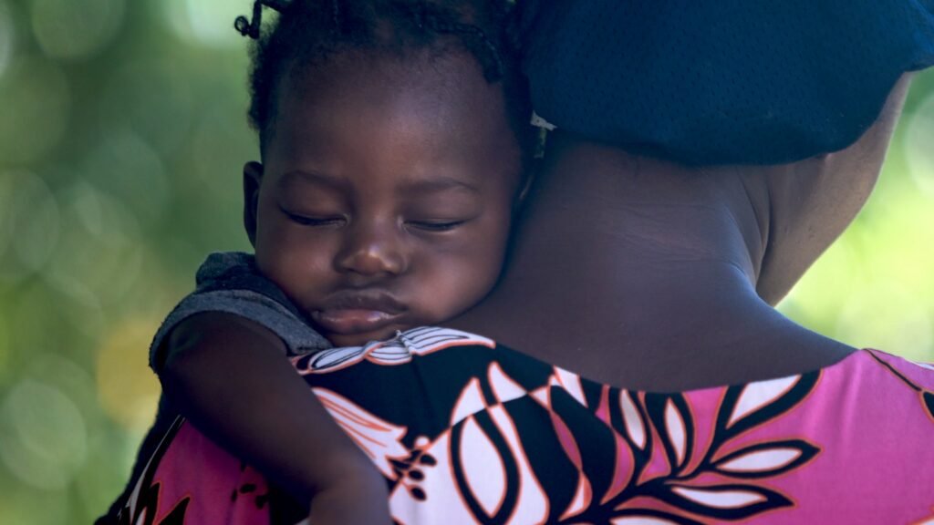 Child sleeping in mother's arms, head on her shoulder