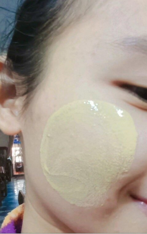 Johana's face with the yellow cream rubbed onto her cheek