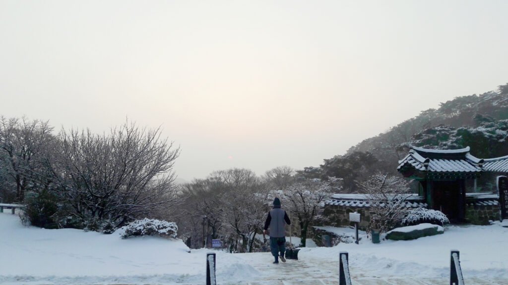 JP Morselli standing off in the distance in a snow capped terraine with a Korean temple nearby