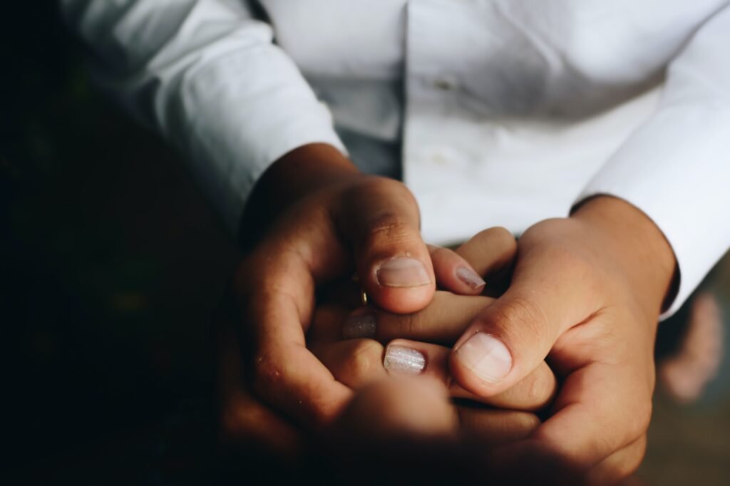 Two sets of hands clasped together; one an adult and the other a child's