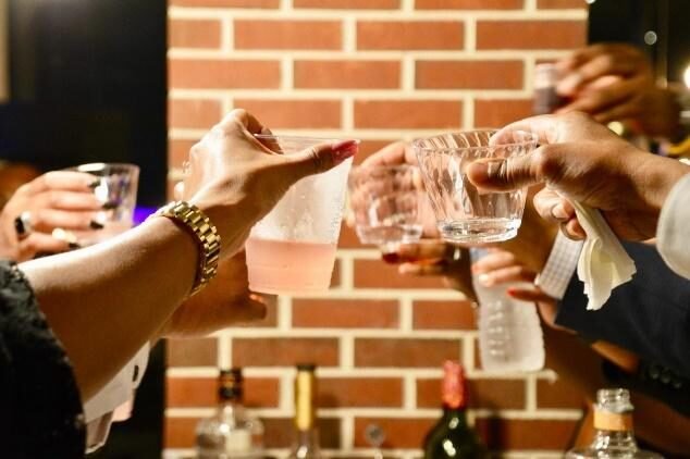 Hands holding shot glasses and toasting in a pub