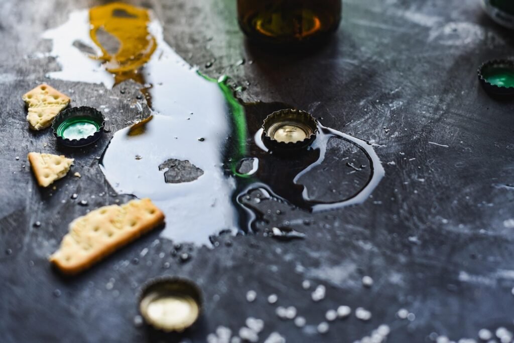 Alcohol spilled on a table with broken crackers on the table