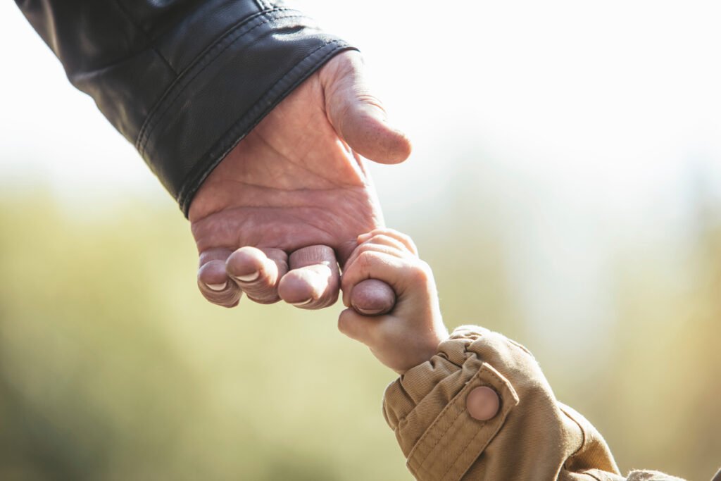 Baby girl warm jacket and cap c grandfather hands in autumn Park