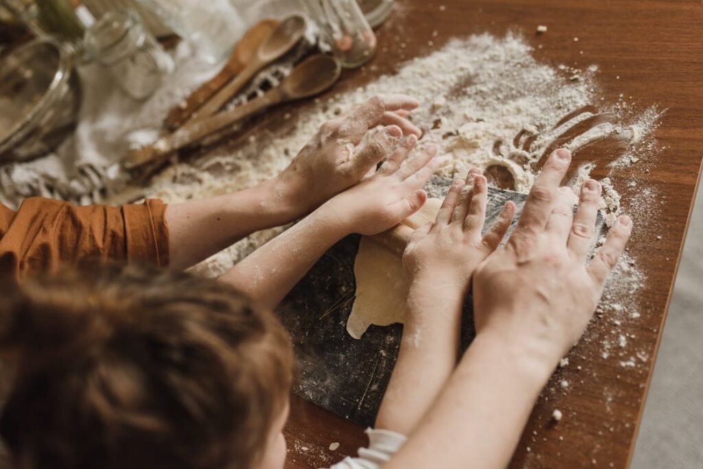 an adult and child's hands baking together