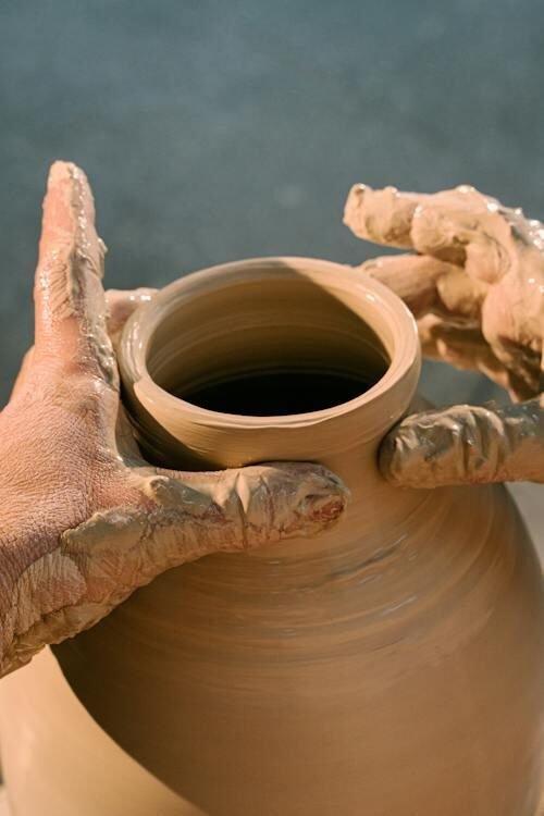 two hands working on a pottery machine