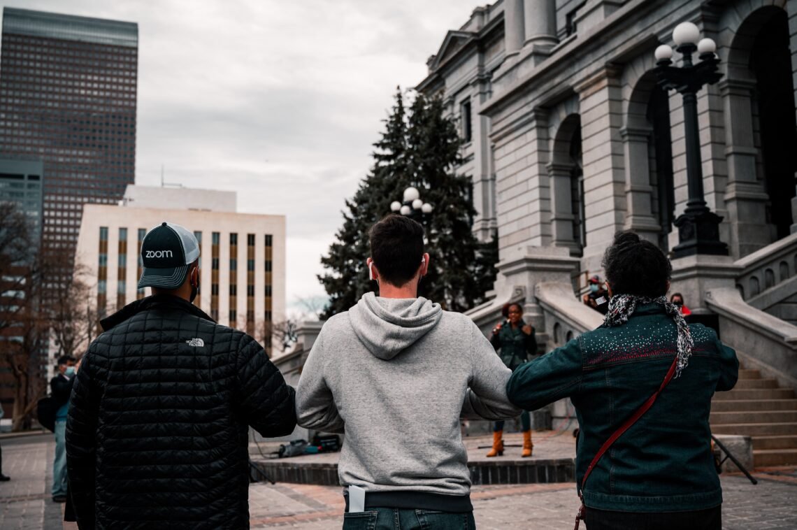 Three adults locking arms in front of building