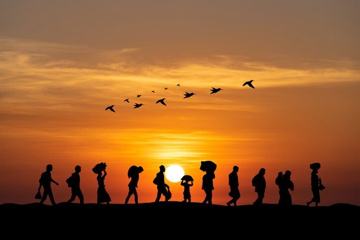 Immigrants crossing the horizon with the sun setting in the back