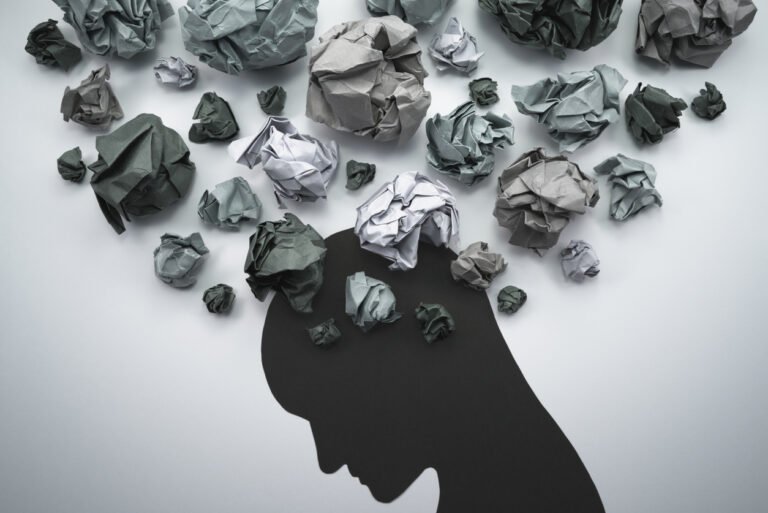 silhouette of a head with crumpled papers floating above it
