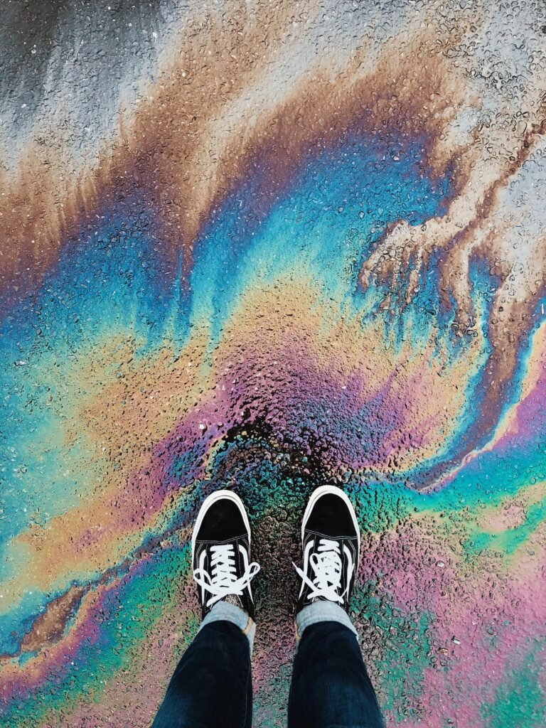 Someone's view of their sneakers standing on rainbow pavement