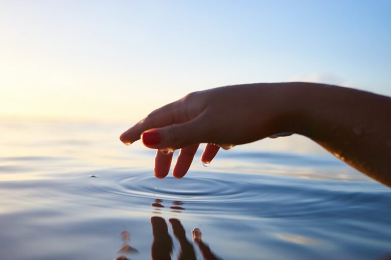 Hand touching the surface of lake water