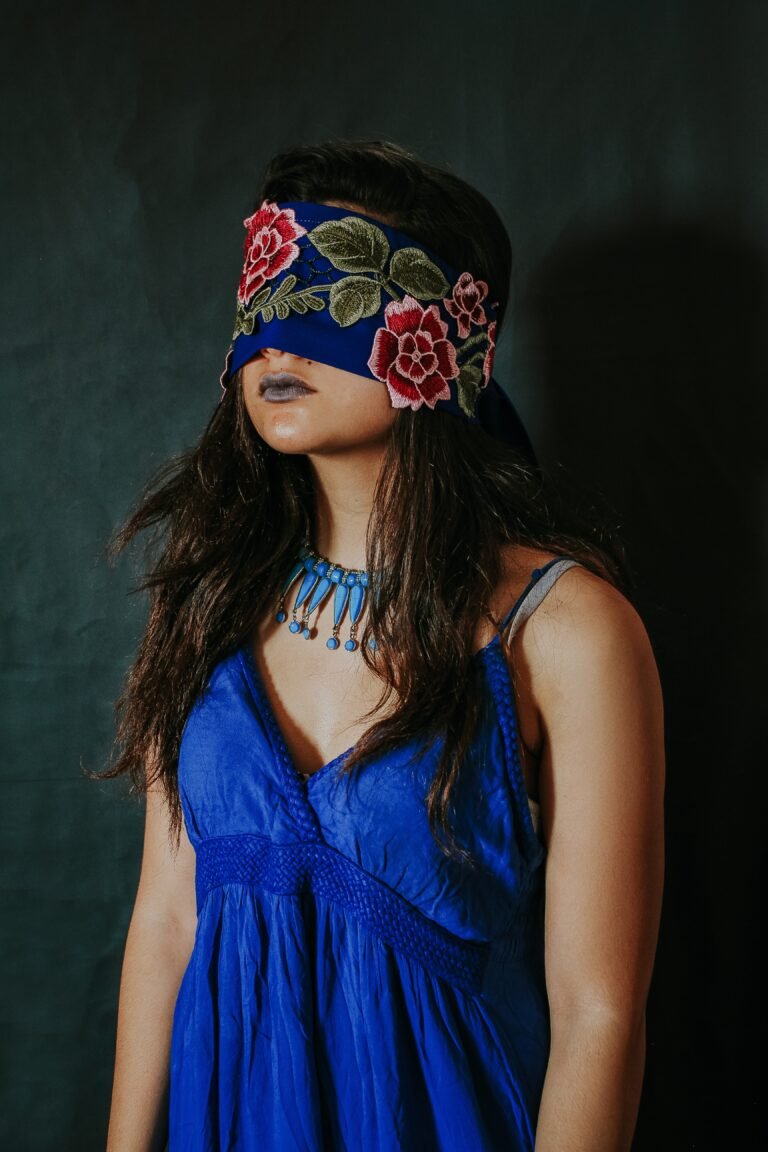 Woman wearing a blue dress and she is blindfolded