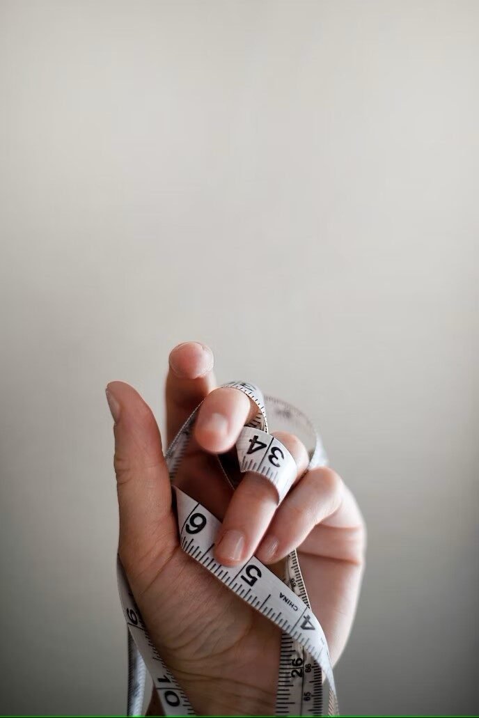 Single hand holding measuring tape, with the tape wrapped around the hand