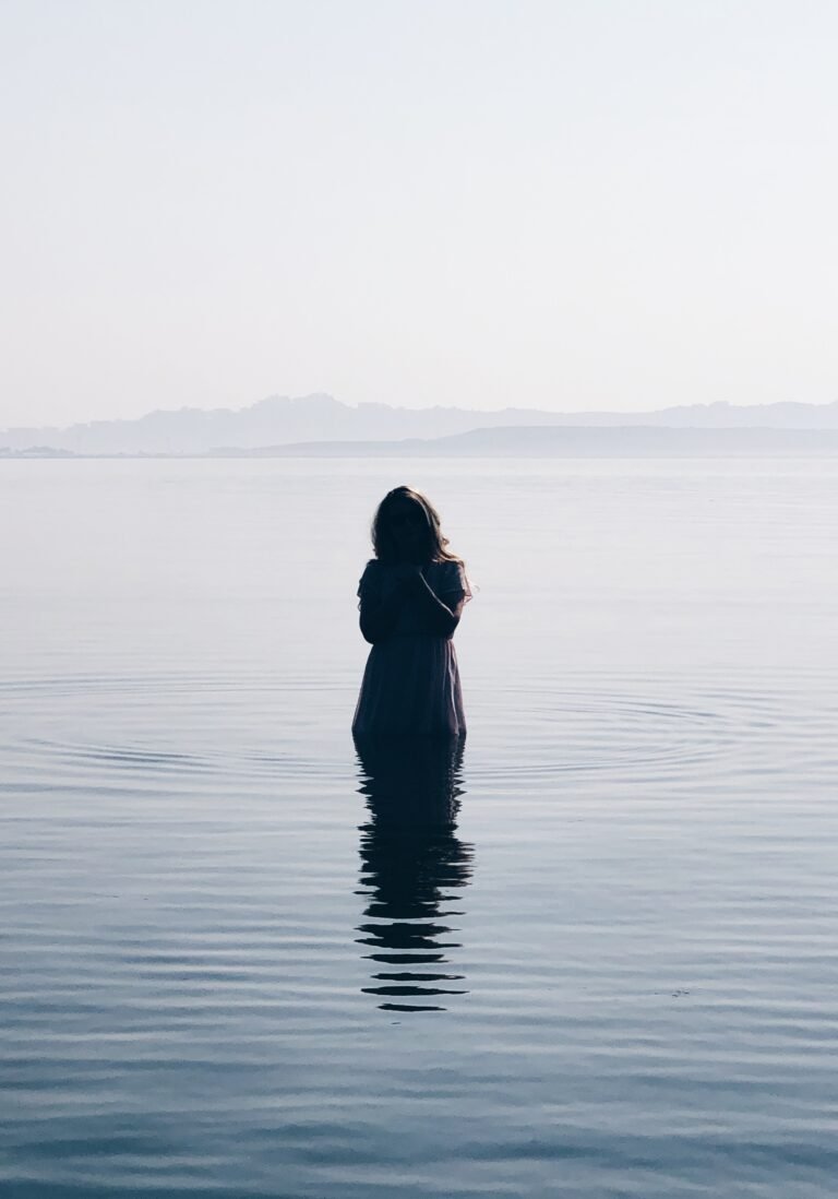 a woman standing in the middle of a lake.