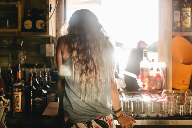 A woman facing the bar and ordering a drink