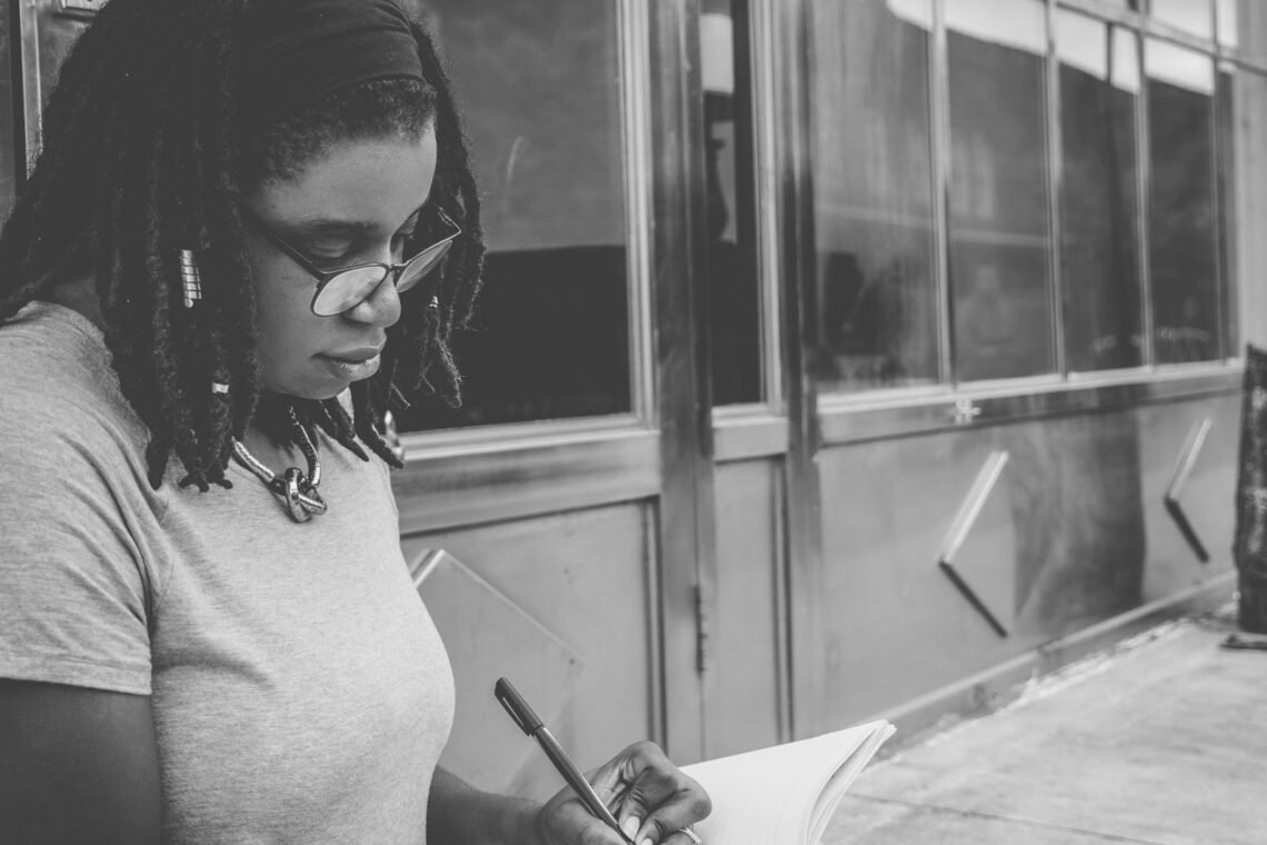 black and white image of a woman writing on a piece of paper