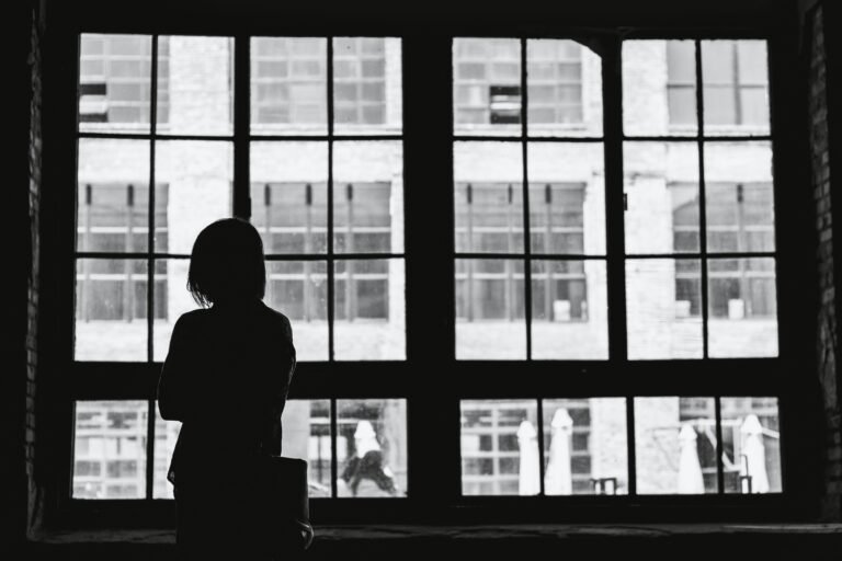 a silhouette of a woman standing in front of windows