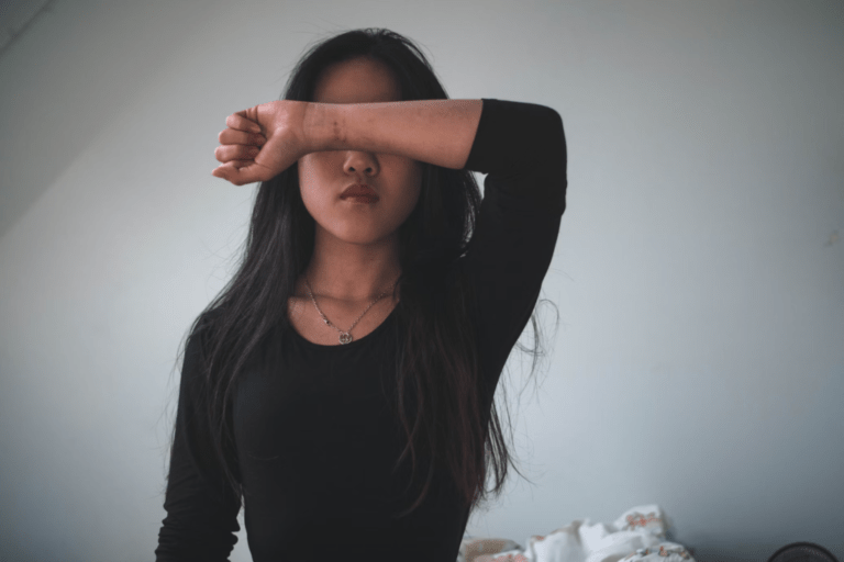 an asian woman holding her forearm over her eyes
