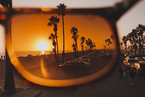 sunset view of the beach and parking lot with palm trees lining the sidewalk